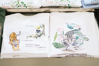 Two white folded fabrics with drawings of an adult tiger and a tiger cub among greenery.