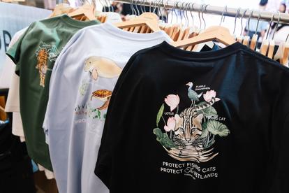 Row of graphic t-shirts on a clothing rack; front black tee features a floral animal design.