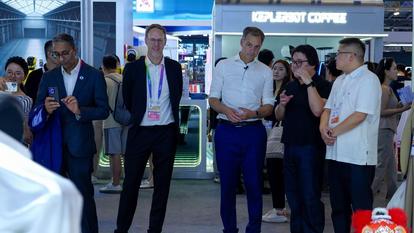 Group of professionals at a blue trade show booth, wearing badges.