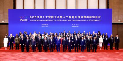 Group of formally dressed officials posing on stage in front of a blue conference banner.