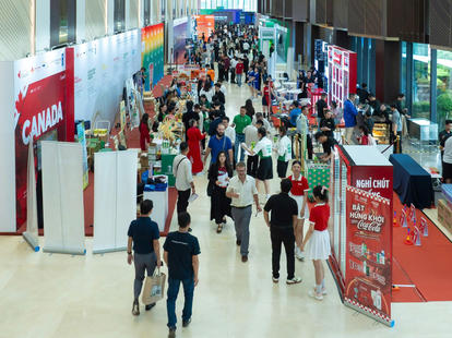 Photo of a crowded indoor trade show hallway with colorful booths and banners.