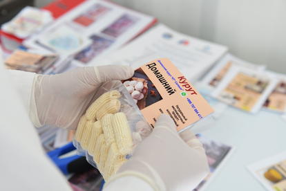 Gloved hands hold a small ID card with a photo, with more cards on a table.