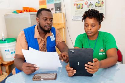Two people at a table reviewing papers and a tablet.