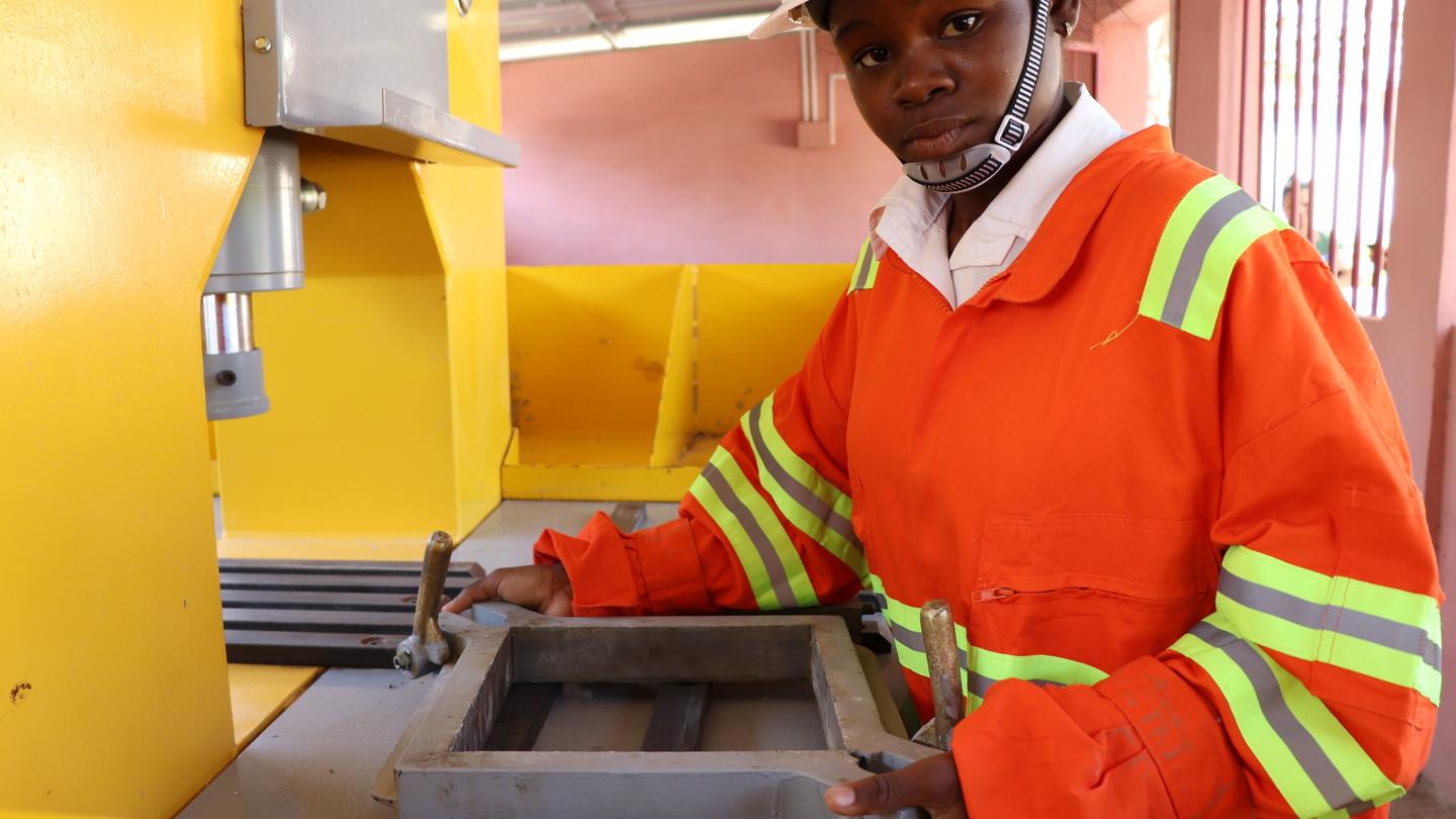 mujer joven estudiante de la especialidad de construcción en la enseñanza técnica y profesional,  preparando la máquina de mosaicos para realizar sus prácticas