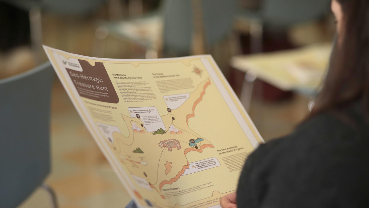 A person holds a colorful informational pamphlet in a seating area.