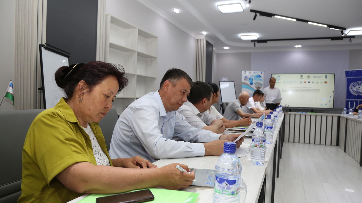A group of professionals engaged in discussion at a conference table, taking notes.