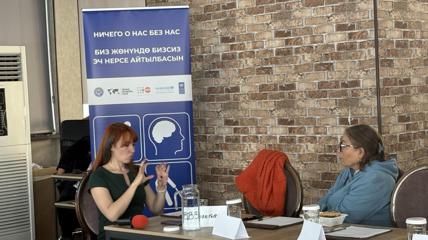 Panel discussion with three people seated at a table in front of a brick wall.