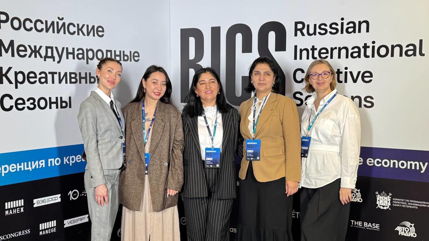 Four women with lanyards smiling at a conference booth for Russian International Creative Season.