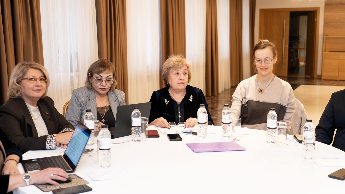 Photograph of professionals around a conference table with laptops.