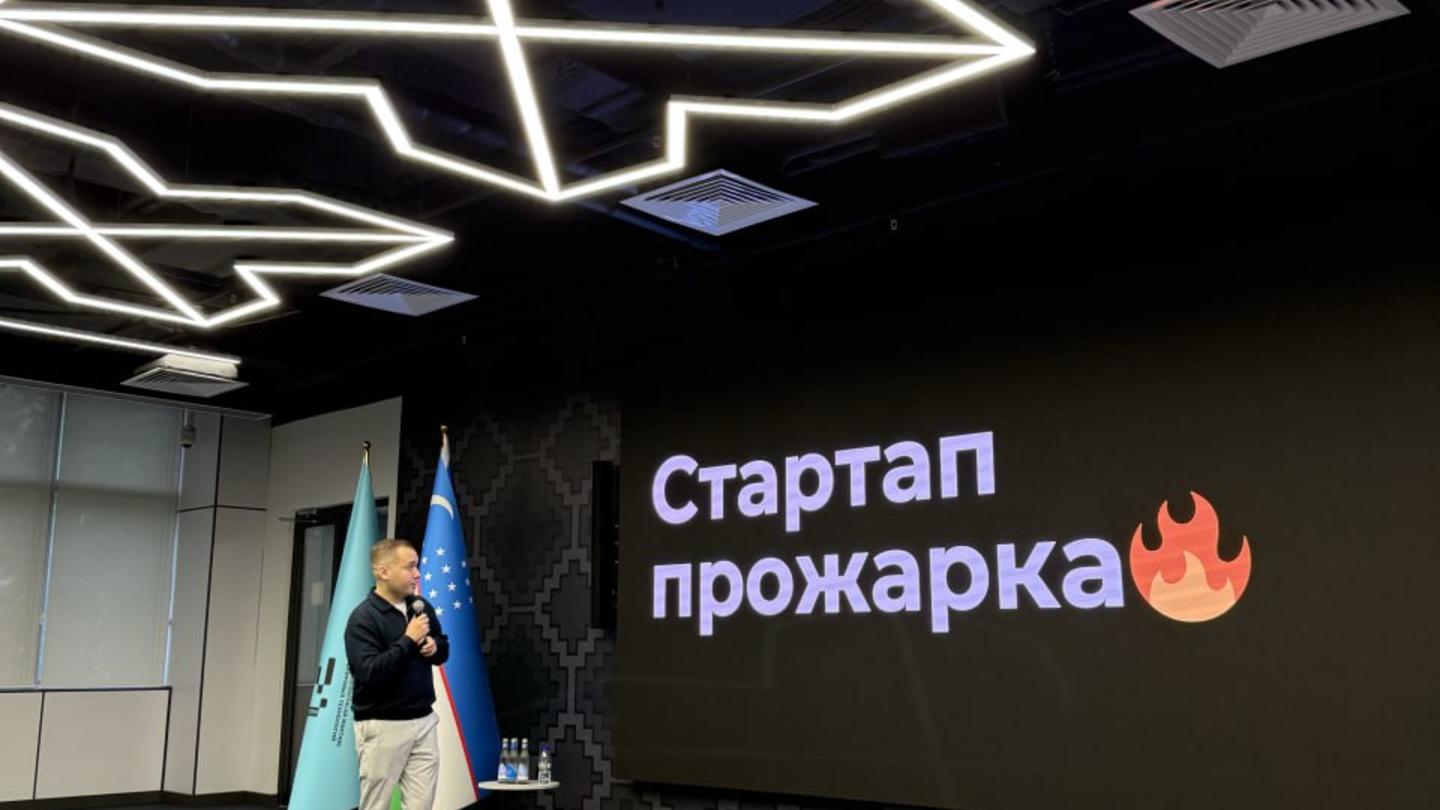 Person walks through a modern startup space with star-shaped neon ceiling and Cyrillic wall sign.
