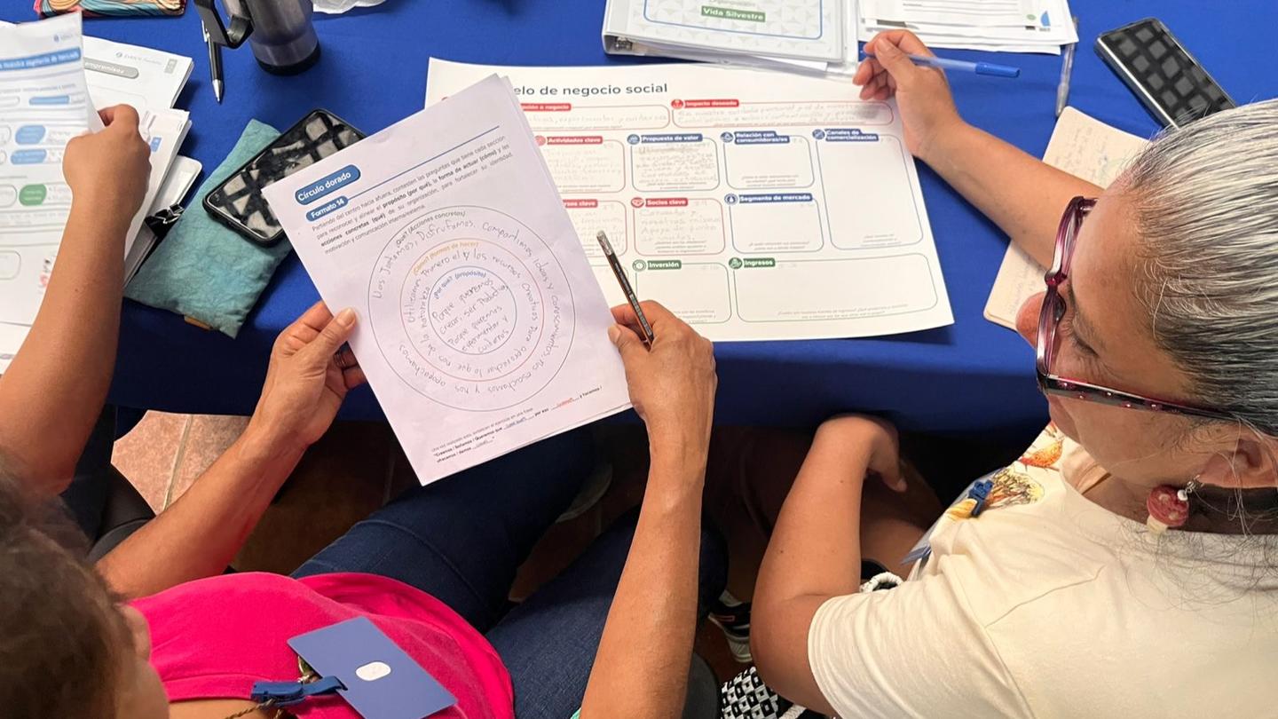 Group around a blue table examining printed worksheets with charts.