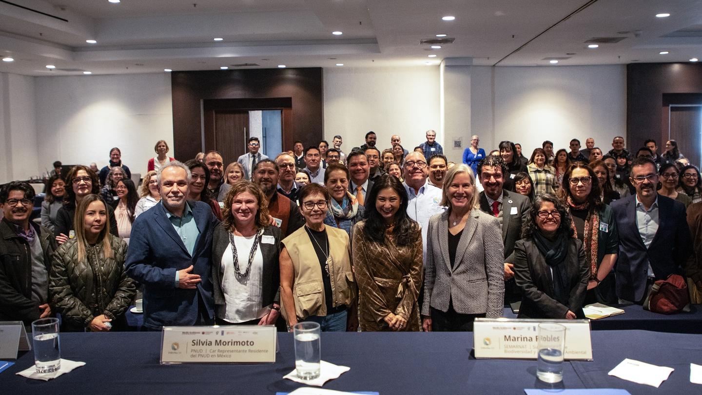 Crowd of attendees posing for a large group photo in a conference room.