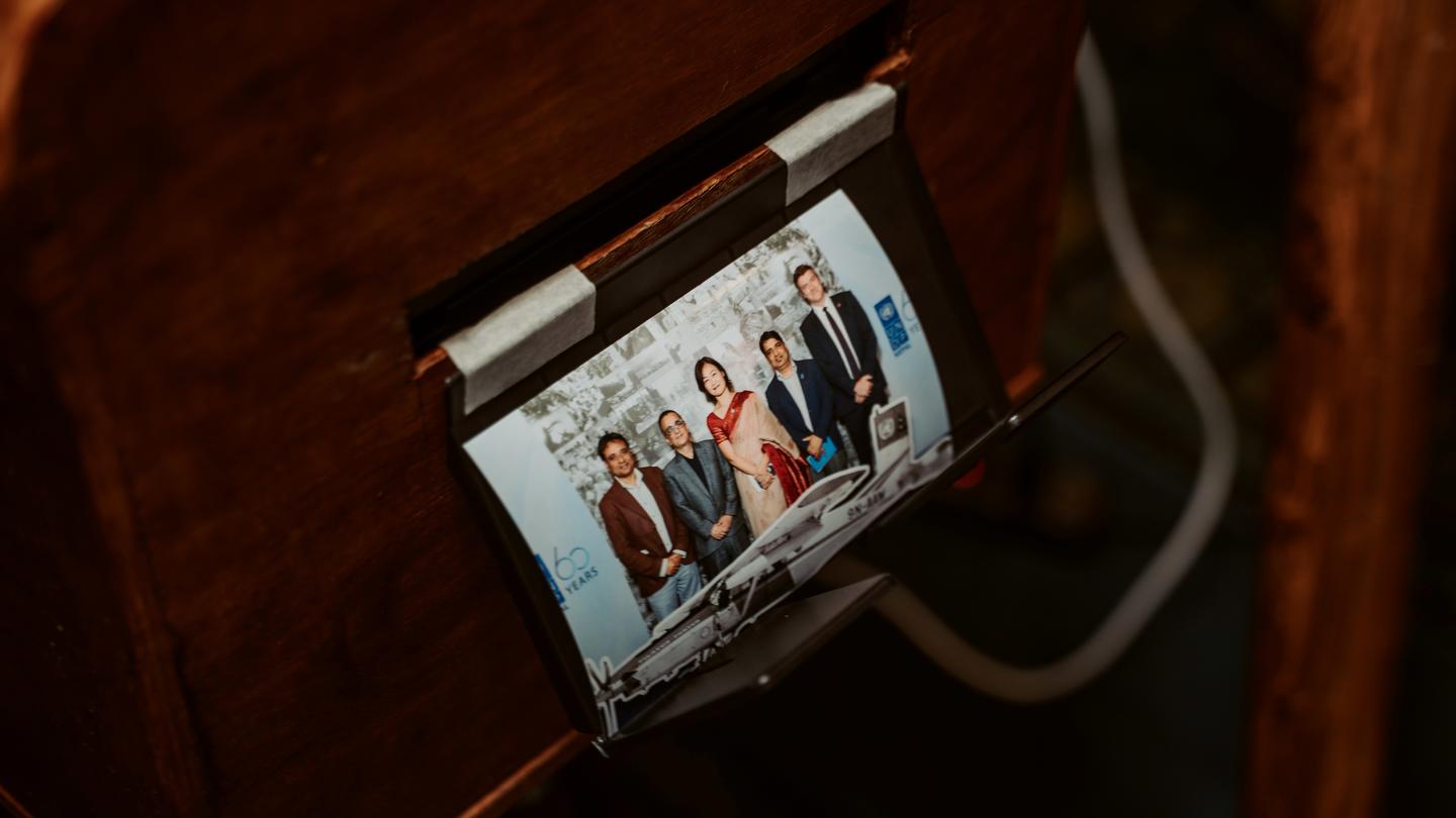 Smartphone on a wooden desk showing a group of people in a video call.