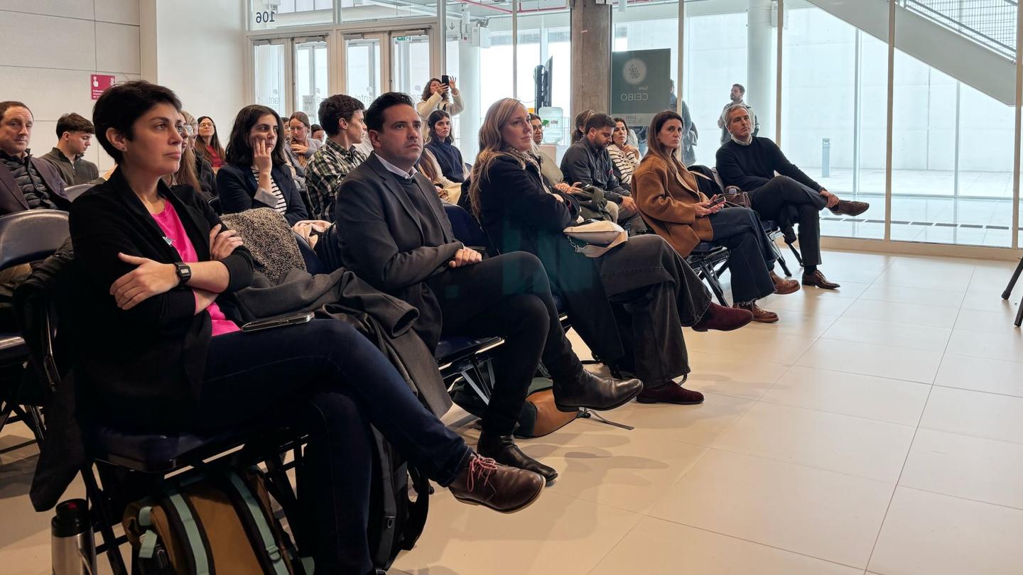 Photograph of a diverse audience seated in rows in a bright conference room.