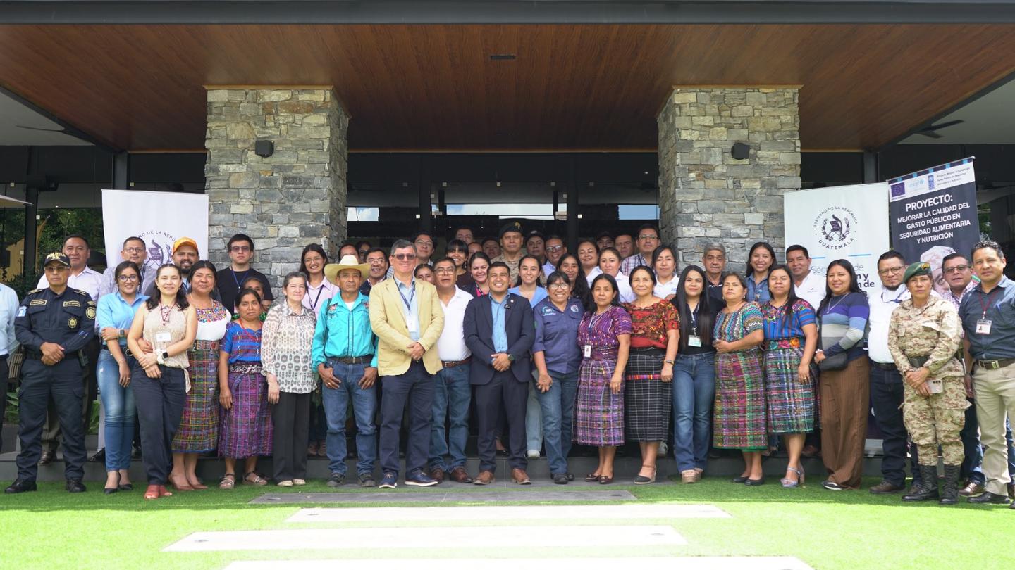 Group photo of a diverse crowd posing outside a stone building with columns.