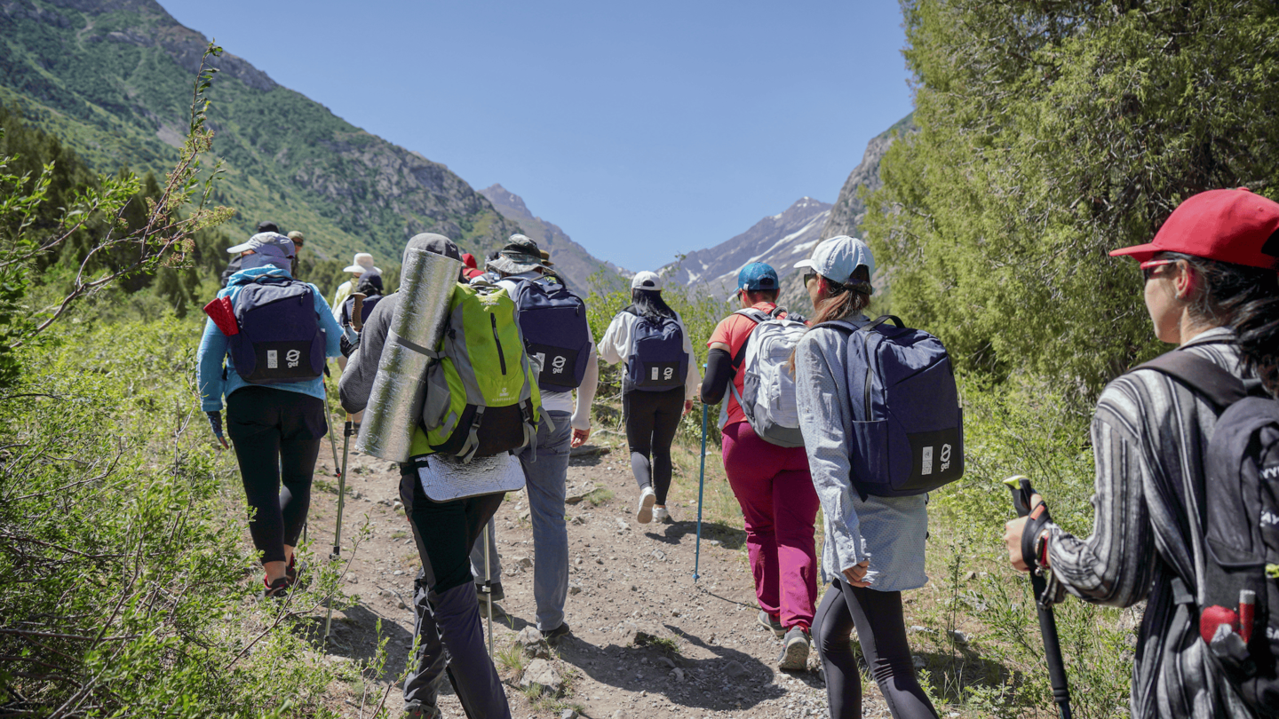 Group of hikers with backpacks trekking along a rocky mountain trail.