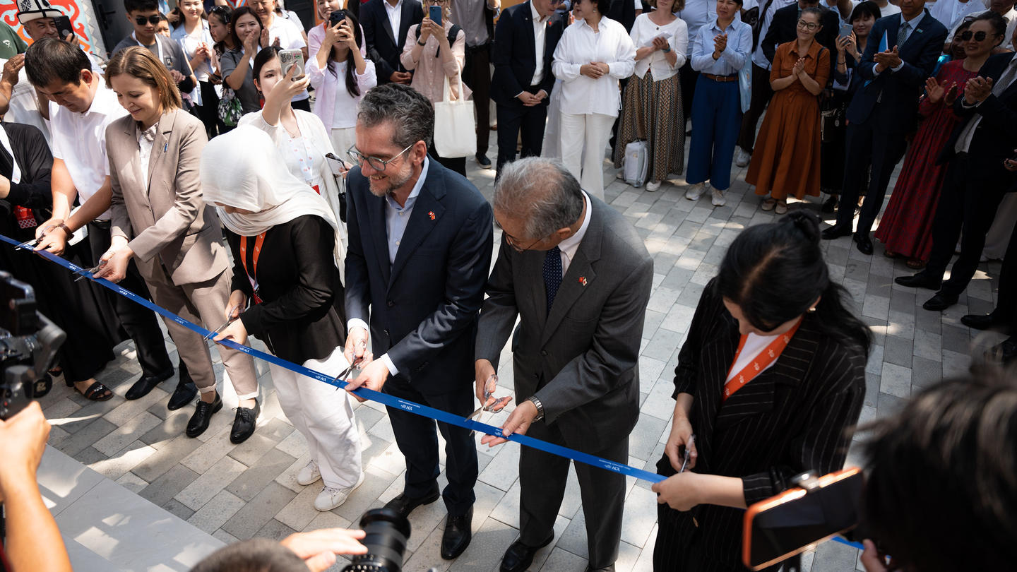 Photograph: Officials cut a blue ribbon at a ceremony, crowd watches.