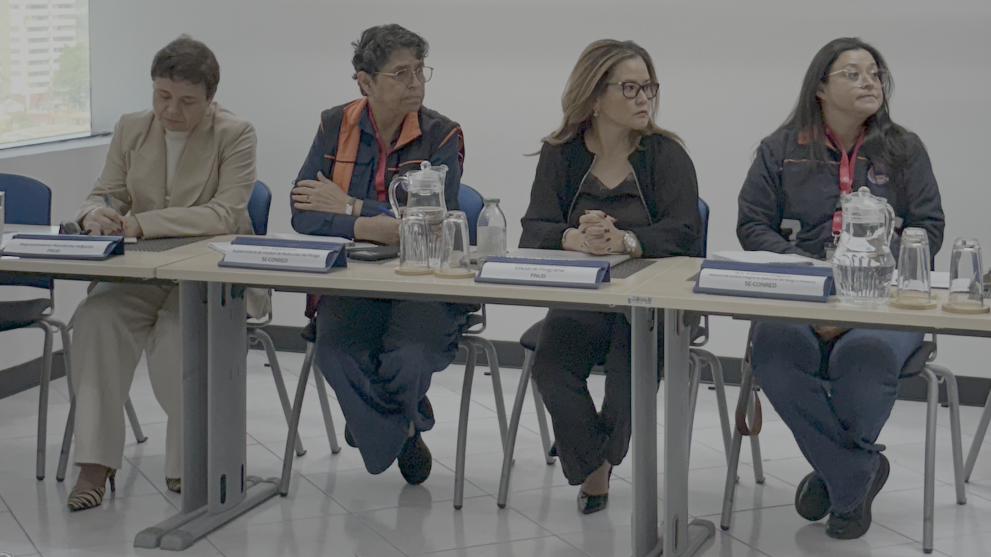 Five people seated at a long conference table with papers and water bottles.