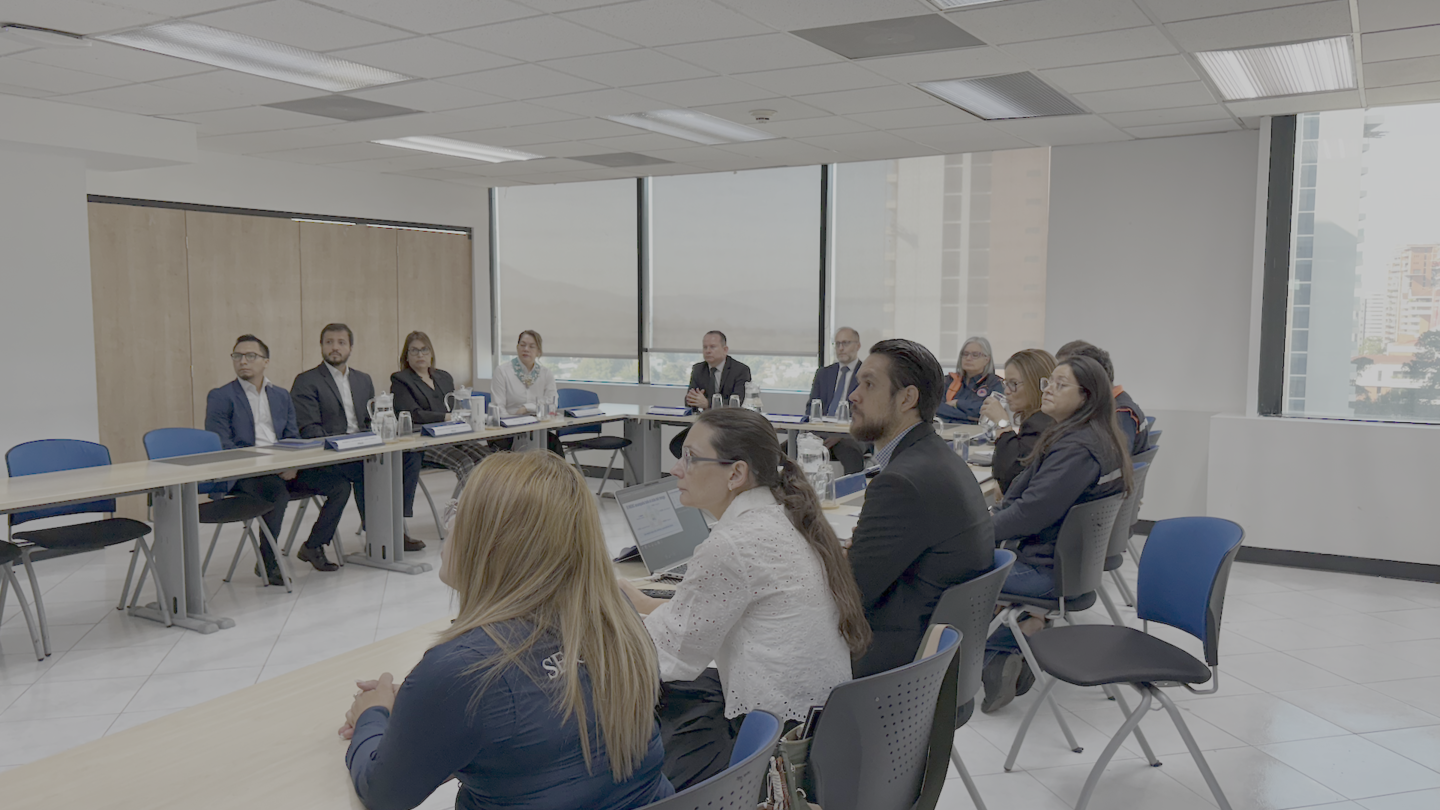 People seated around a long conference table in a bright office meeting room.