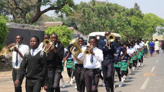 The Jacaranda School Brass Band marches down the street giving the high-table a tour of the infrastructural improvements meant to slow road traffic/speeding outside the school