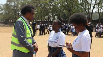 Dr Saleban Omar engaging with 2 students of Jacaranda Combined School at the Launch of Safe Schools Infrastructural Improvements in Lusaka