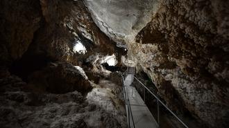 Dimly lit cave interior with rock formations and a metal walkway.