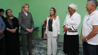 Photograph of diverse people standing together in a studio with a green backdrop.