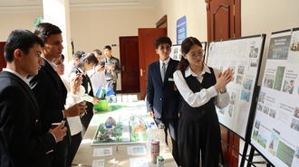 Group of people at a poster presentation, examining display boards in a bright hallway.
