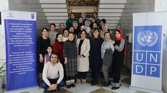 Group of people posing for a UNDP event indoors beside banners.