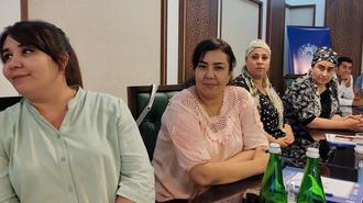 Group of people around a conference table in a meeting room, with green glass water bottles.