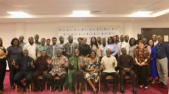 Large diverse group of people in formal attire posing for a group photo in a conference room.
