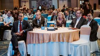 Photograph of business conference attendees seated around round tables.