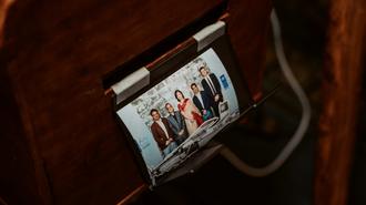Smartphone on a wooden desk showing a group of people in a video call.