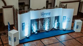 Blue-lit conference stage with curved backdrop, panel desk, and side pillars bearing logos.