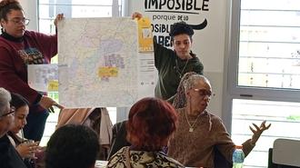 Photograph of a diverse group around a large map on an easel in a meeting room.