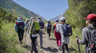 Group of hikers with backpacks trekking along a rocky mountain trail.