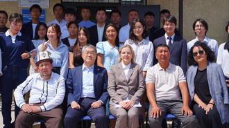 Group photo of many people in business casual on steps outside a building.
