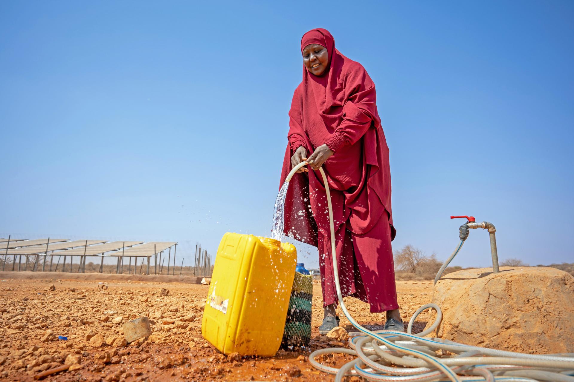 Woman outside pouring water from a hose