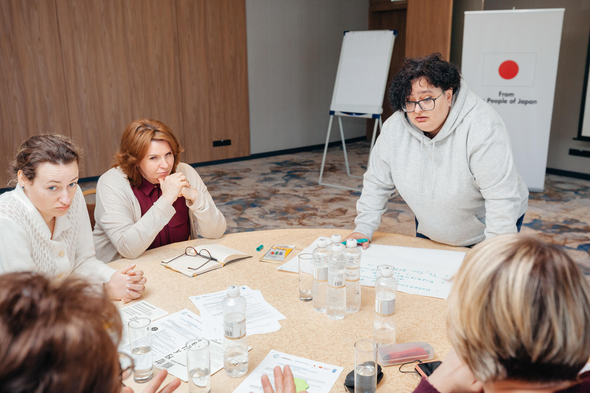 A group of people discussing at the table. A banner with a Japan logo is behind