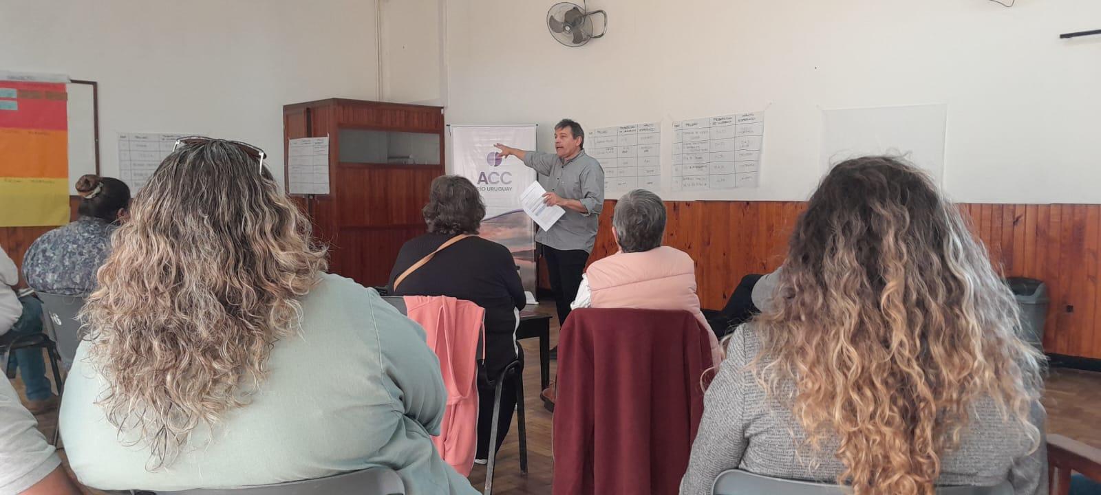 Hombre de pie habla a participantes durante el taller