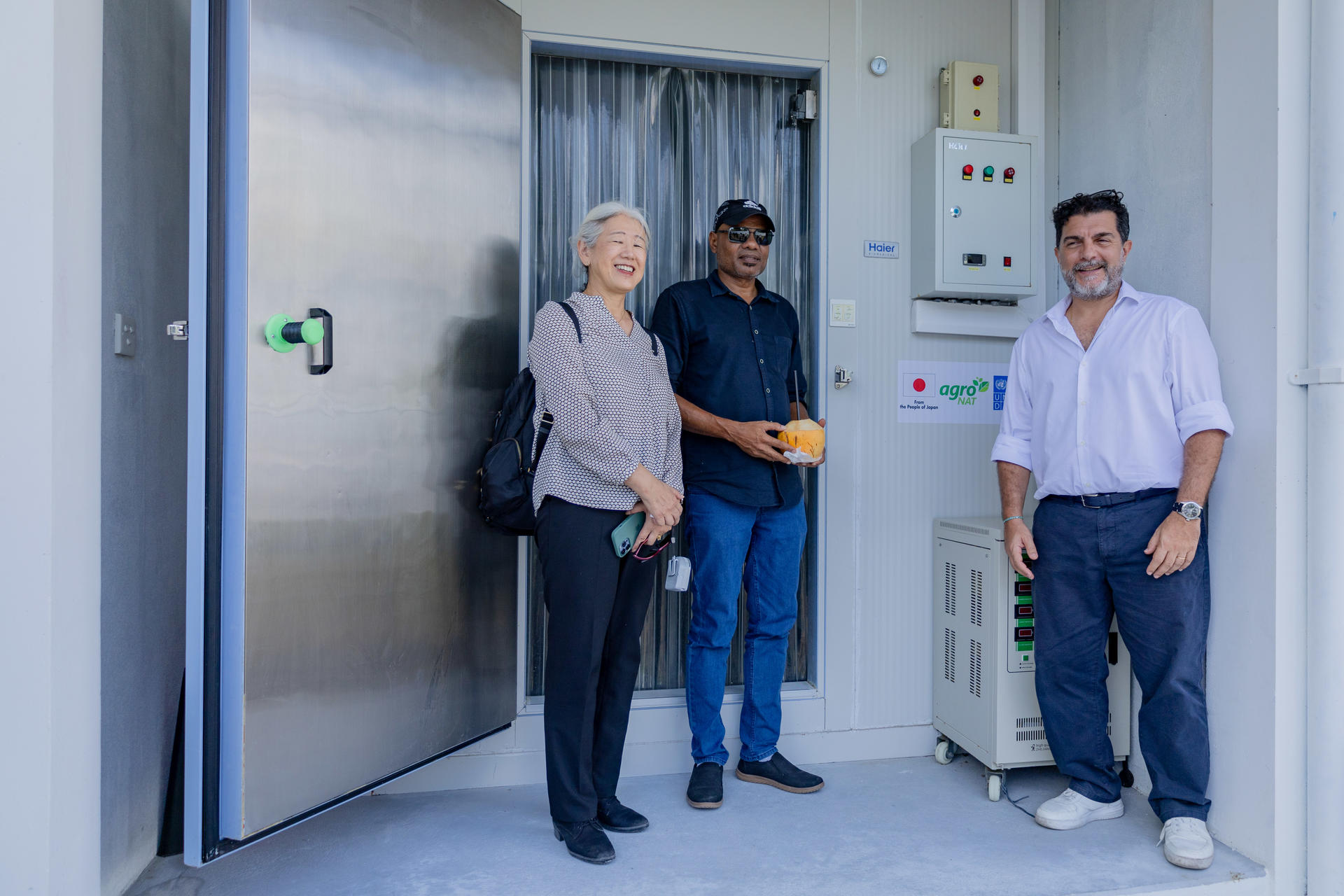 Japanese Ambassador, UNDP Resident Rep and AgroNAT MD standing in front of the cold storage units