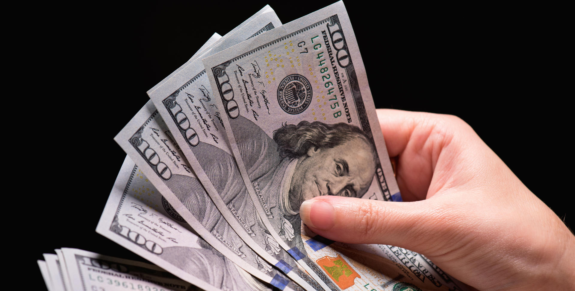 Hand holding $100 bills