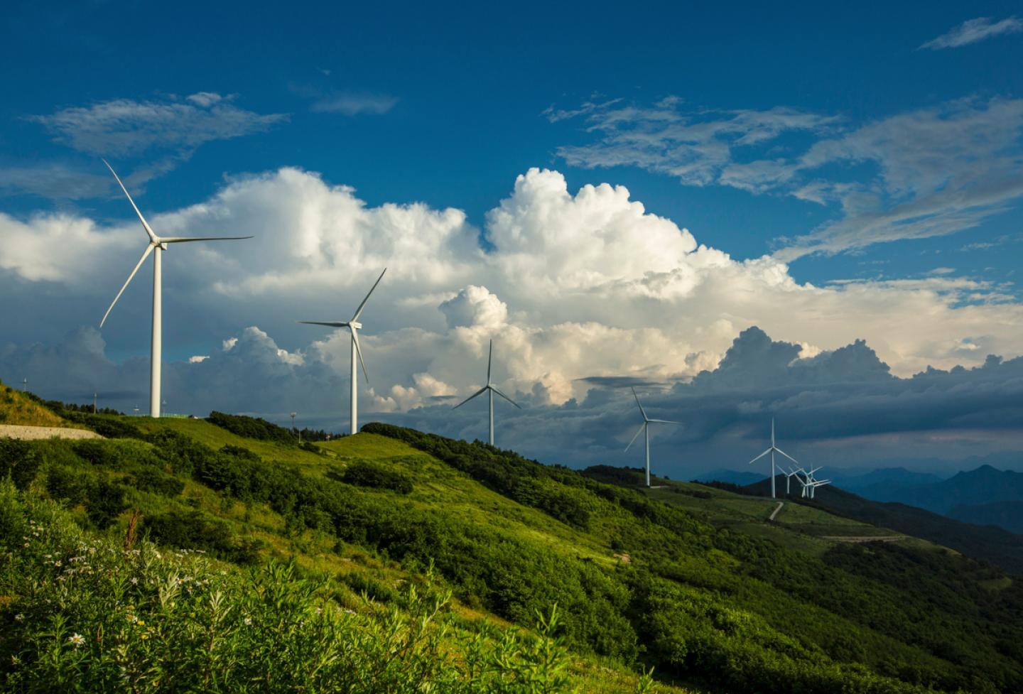 a view of a grassy hill with clouds in the sky