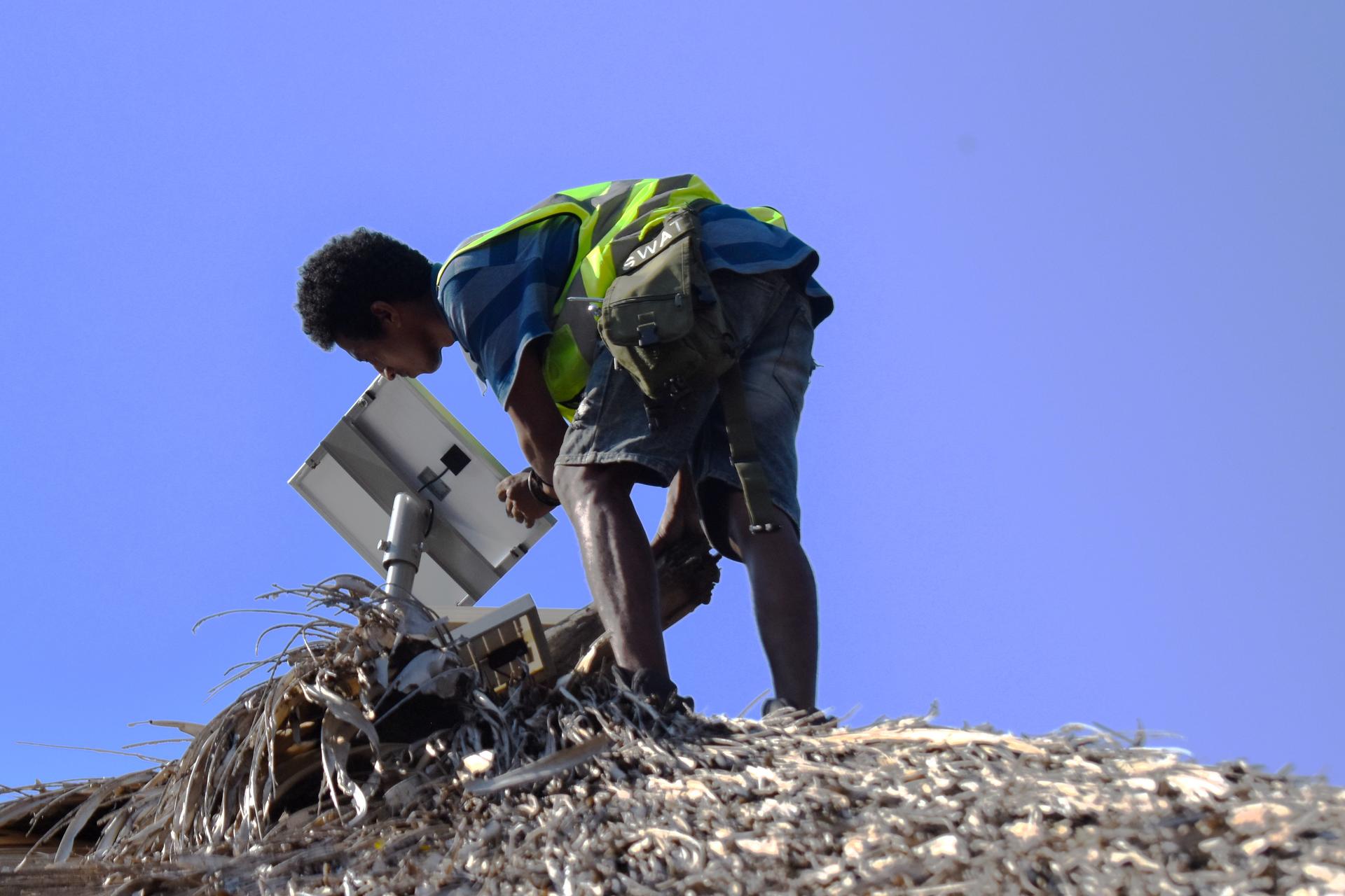 Men installs a solar panel on the rooftop of a house in rural Timor-Leste