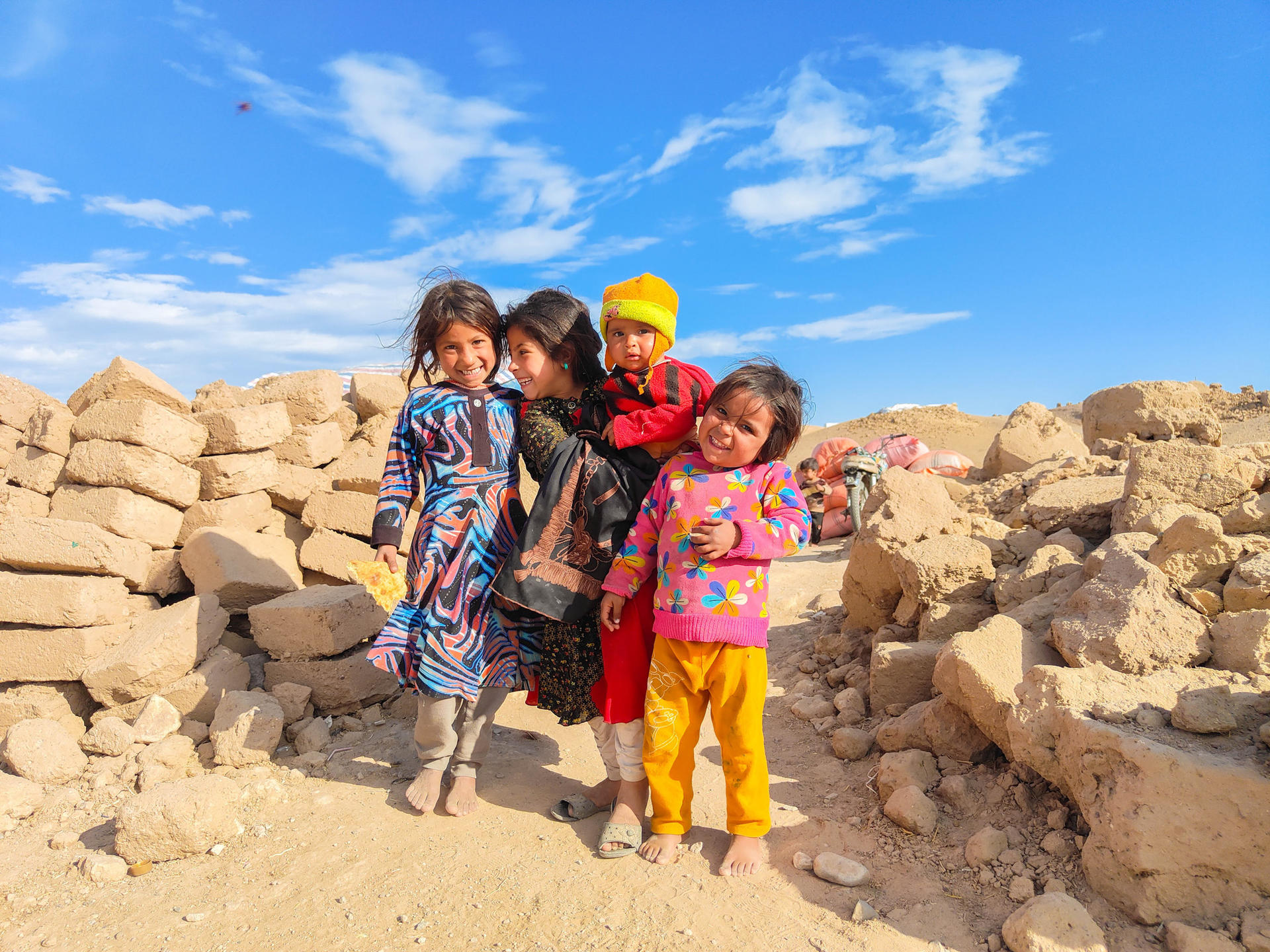 a little girl standing next to a rock