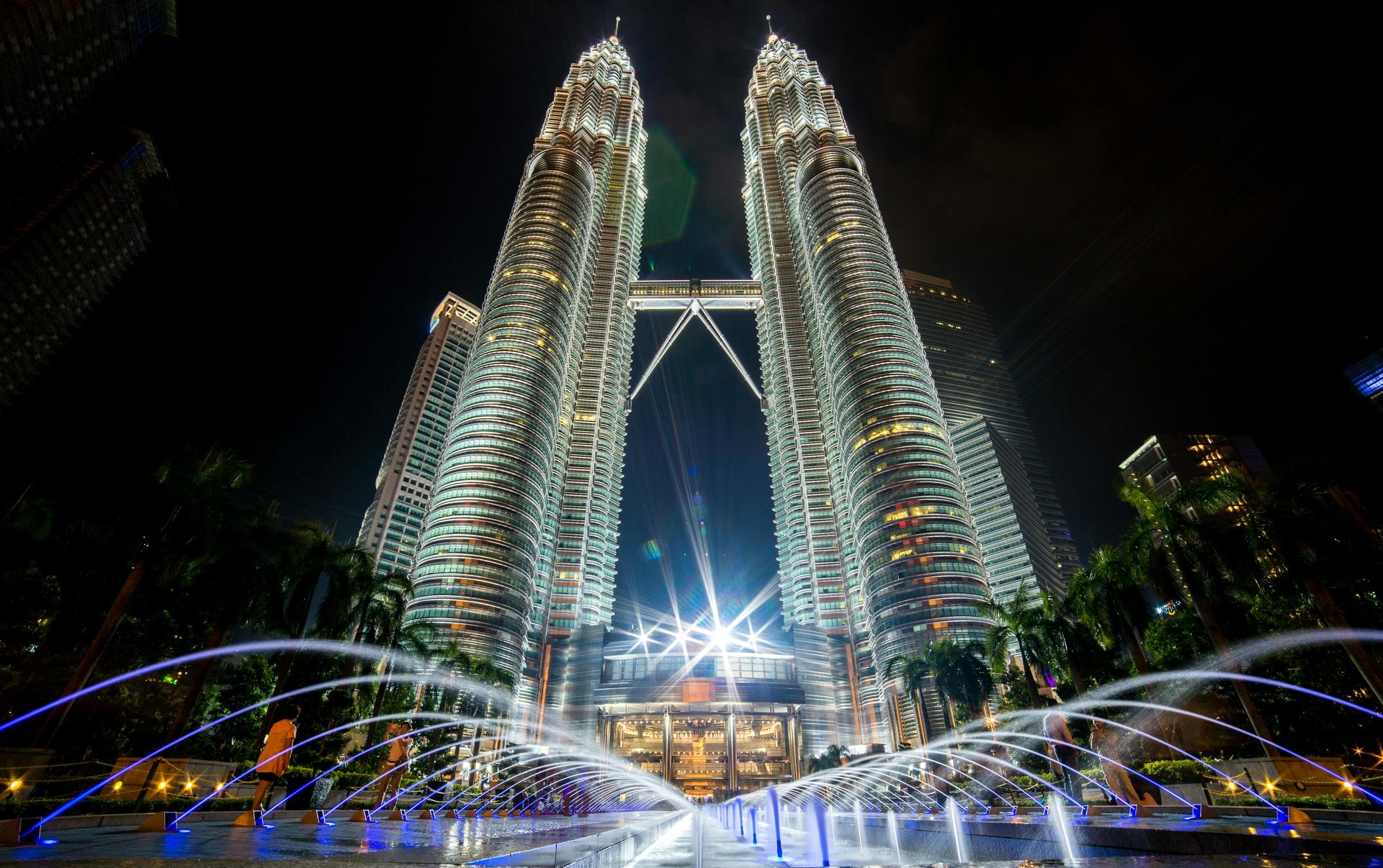 a lit up city at night with Petronas Towers in the background