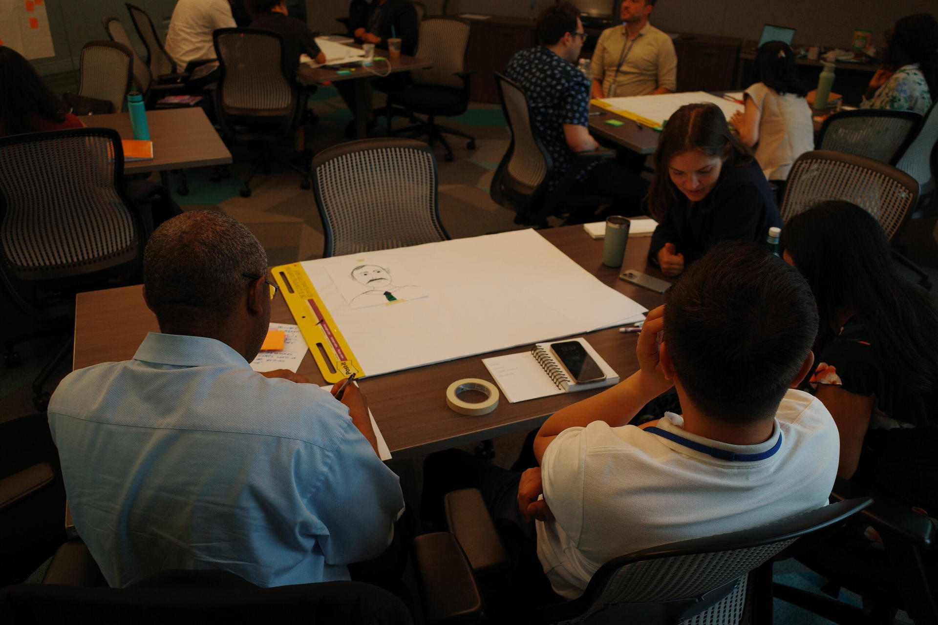 a group of people sitting at a table using a laptop