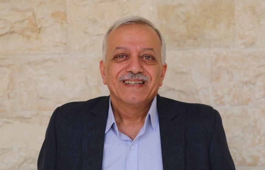 a man wearing a suit and tie smiling at the camera