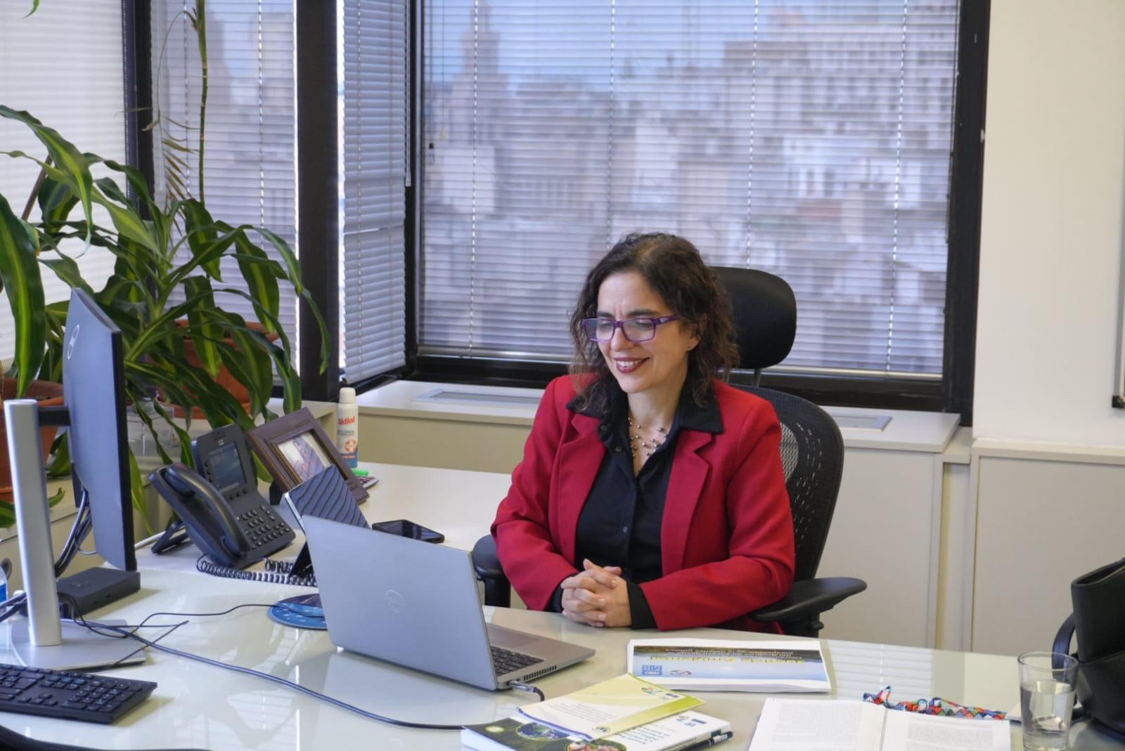 Una mujer sentada en un escritorio frente a una computadora portátil