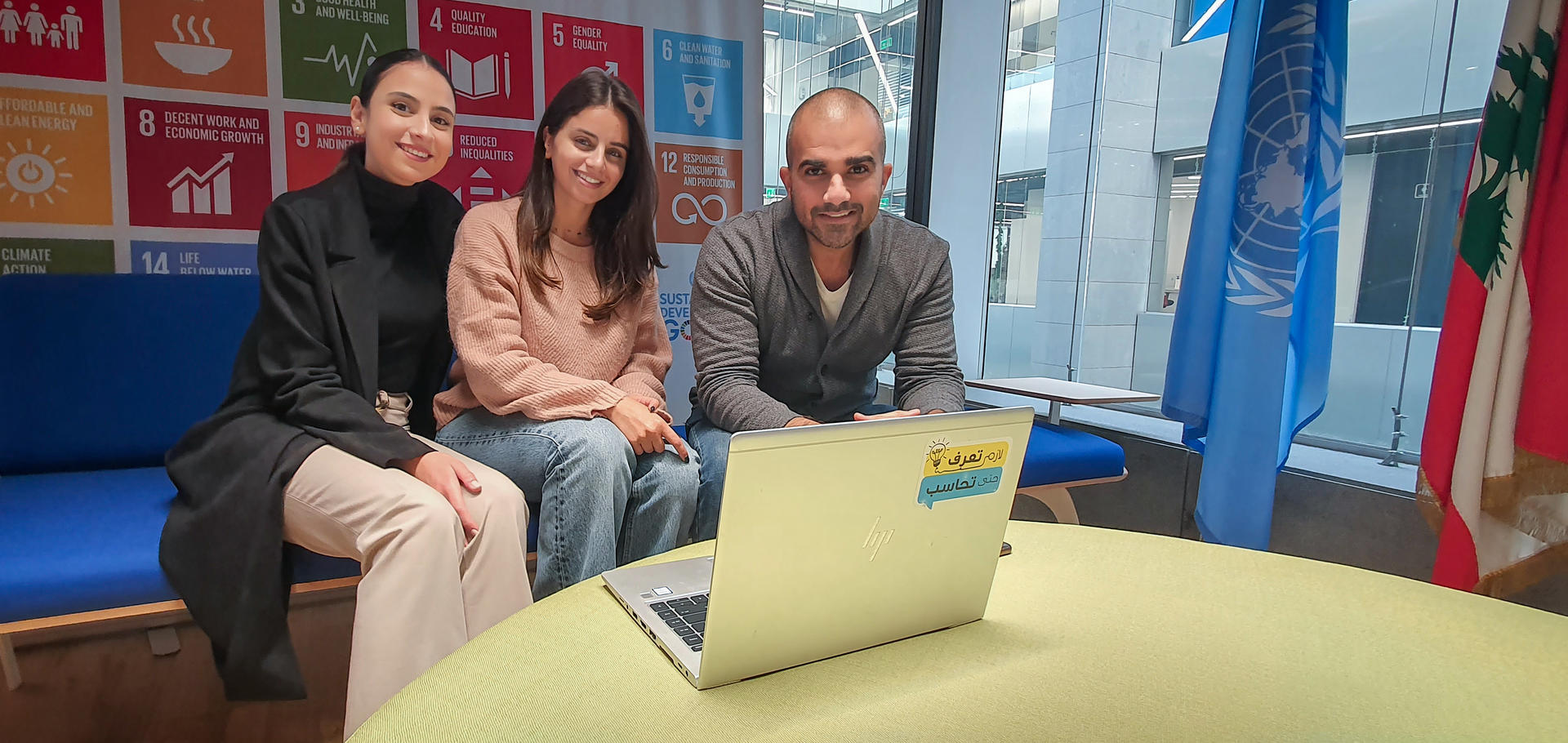 a man and a woman sitting on a bench in front of a laptop